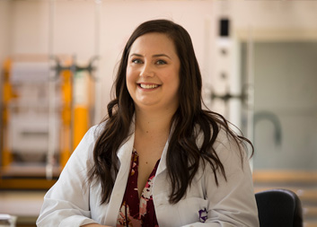 Student wearing lab coat smiling at camera